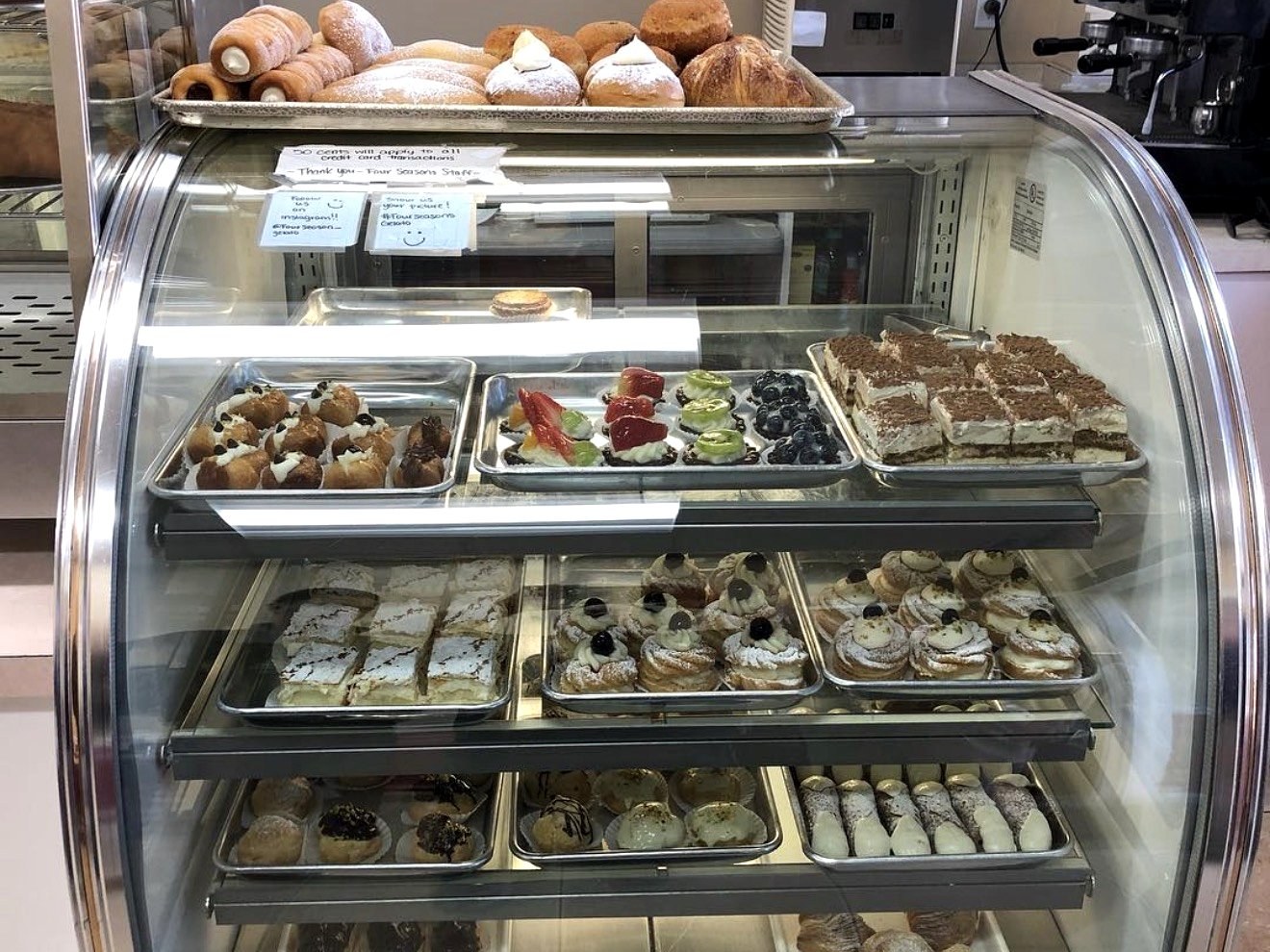Italian pastry display case with cannoli, cream puffs, fruit tarts, and tiramisu at Four Seasons Elmwood Park